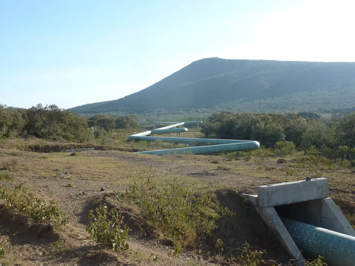 Insulated geothermal steam pipes crossing a culvert below a hill in Hell's Gate