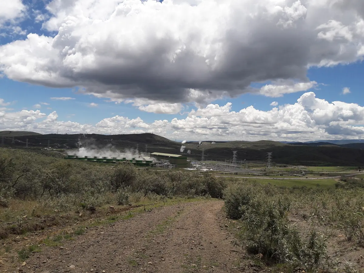 Geothermal power station with steam rising beside a dirt track near Olkaria